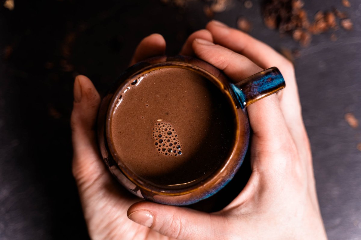 Hände mit einer gefüllten Kakaotasse Zwei Hände halten eine Tasse mit Kakao